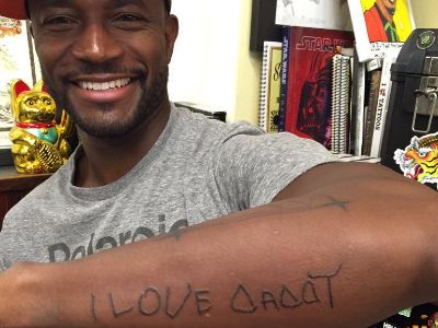 Taye Diggs is smiling showing his tattoo that says I Love Daddy.